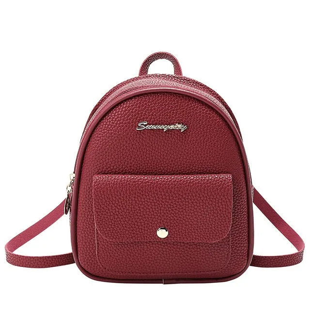 Small black women's PU shoulder backpack worn as backpack, showing zipper closure and compact size