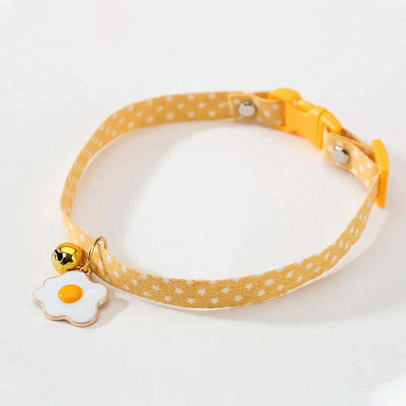 Green adjustable cat collar with a small bell and bow tie pendant on a white background.