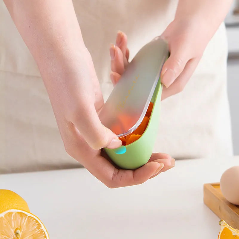 Dark green kitchen peeler with stainless steel blade stored inside its clear plastic storage tube.