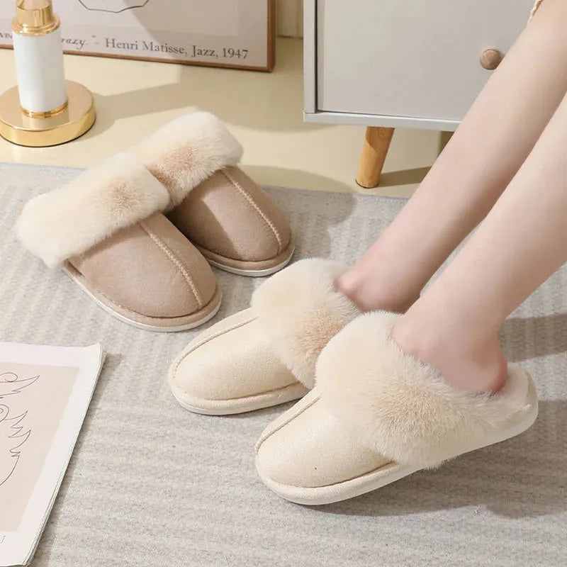A pair of plush indoor slippers with a round toe, flat heel, and stitching detail, shown in one of five available colours.