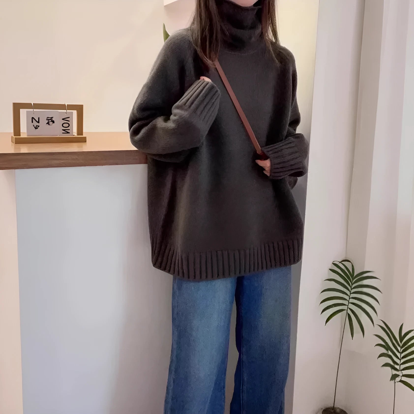 Women's loose grey turtleneck sweater with a thick, textured curling pile collar.