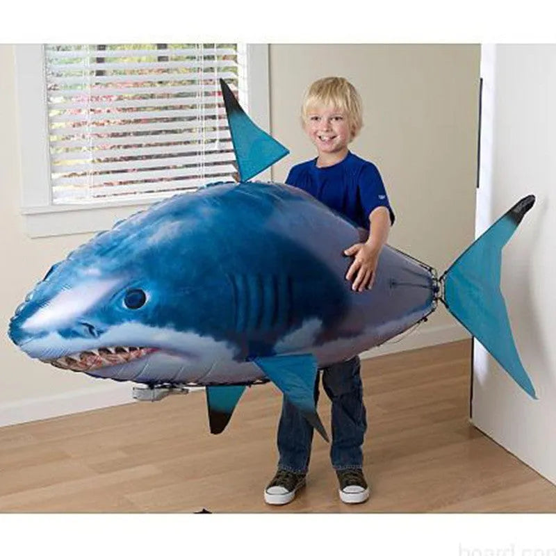 Large remote control shark helium balloon flying indoors with handheld infrared controller.