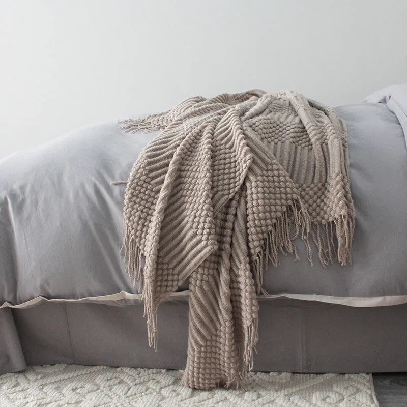 Small light grey polyester nap blanket folded on a sofa, showing its size.
