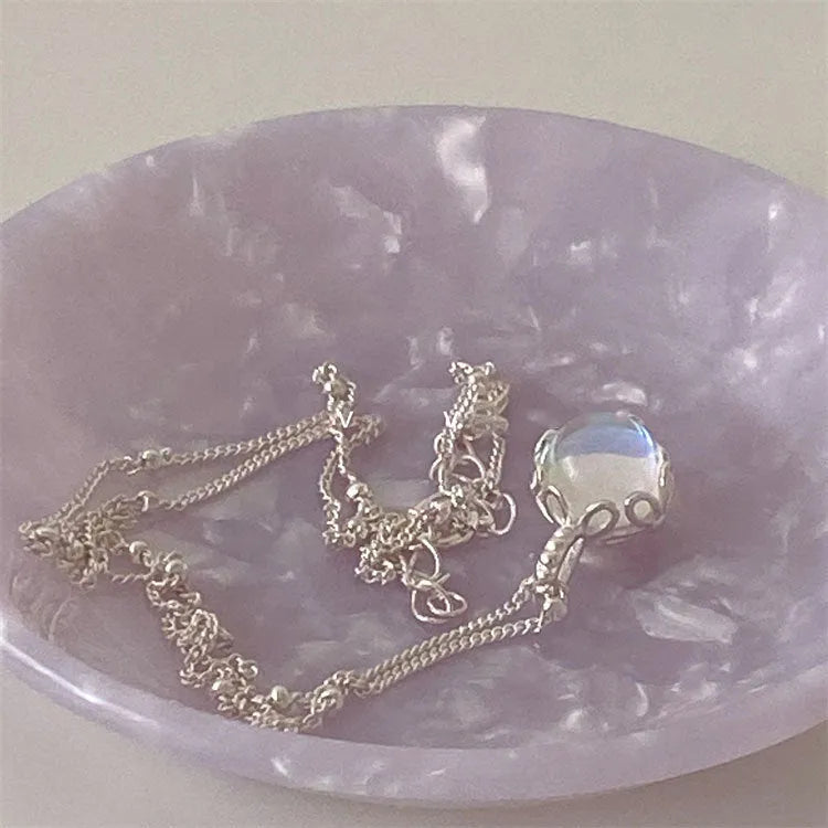 Women's sterling silver curb chain necklace with a geometric ornamental stone pendant on a grey background.