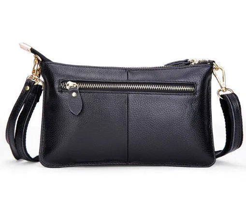 Lady's brown cowhide slant handbag with a long shoulder strap, showing front zip closure.