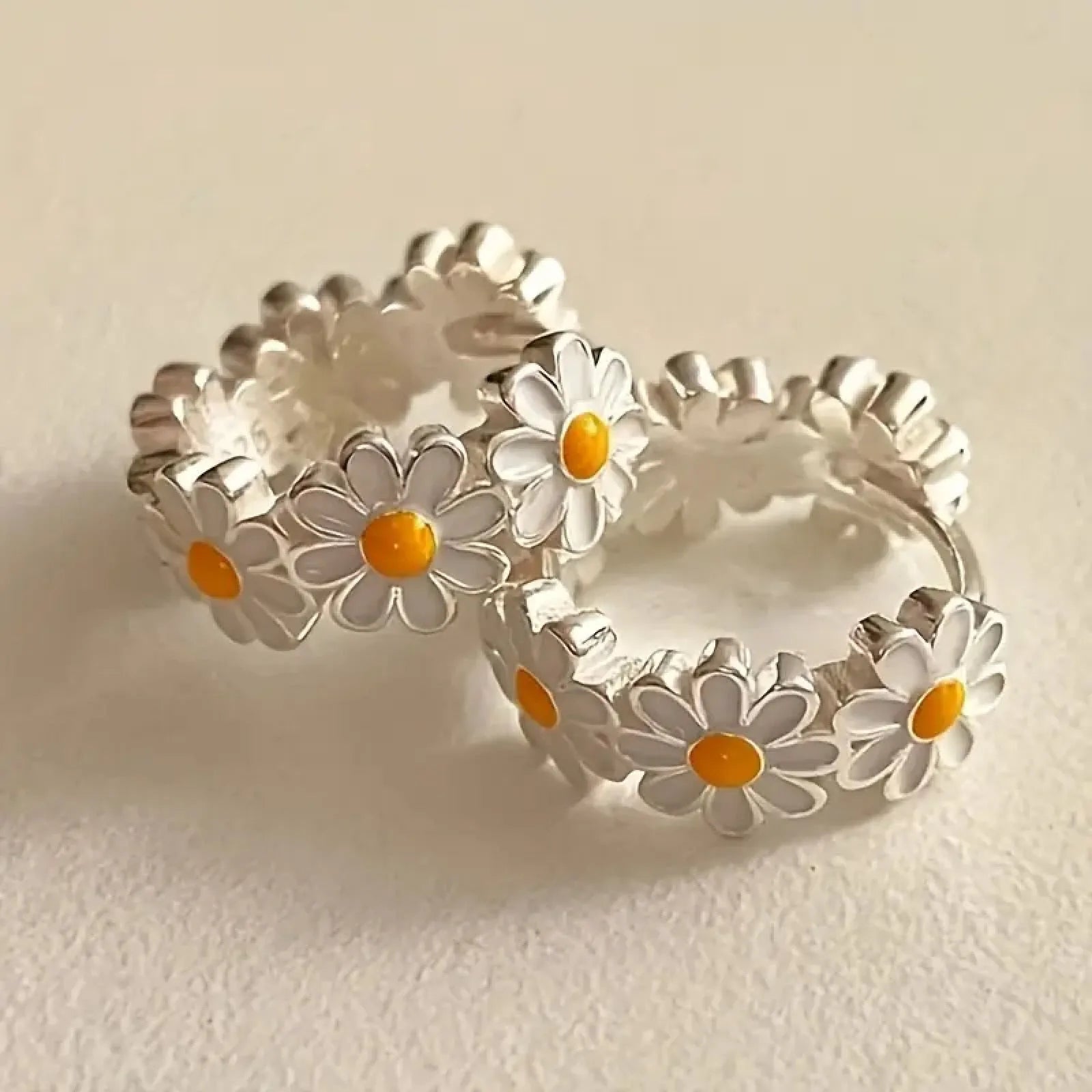 White electroplated daisy flower ring earrings with platinum gem settings on a copper base.
