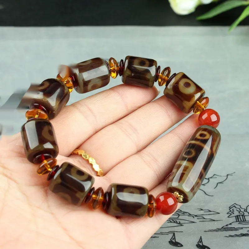 Distressed agate Tibetan bead bracelet with three-eye motifs and polished finish.