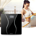 Black electronic bathroom scale with LCD display on a bathroom floor.
