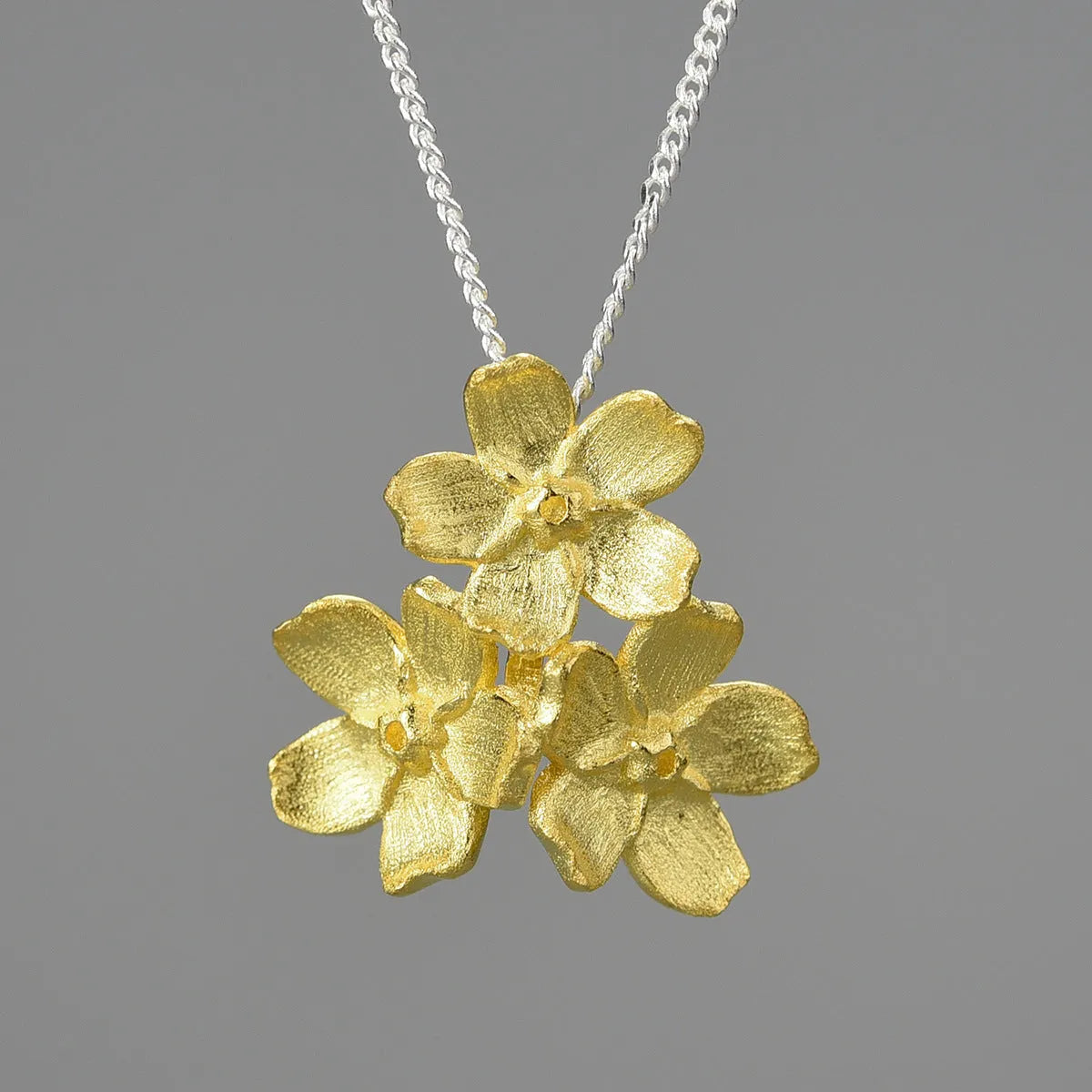 Hand-designed sterling silver Myosotis flower pendant in pastoral style, showing gold and silver colour options.