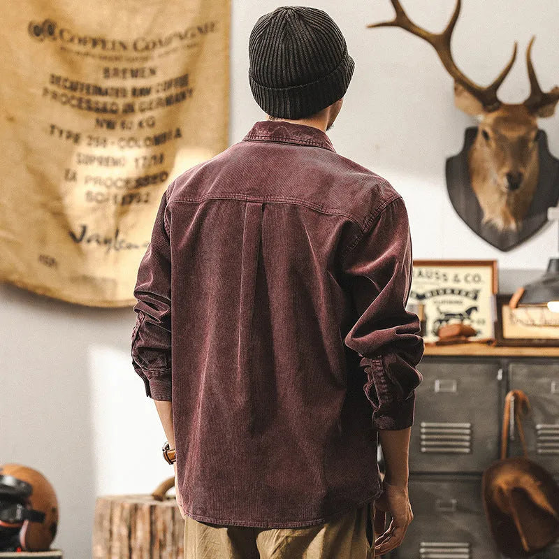 Men's black loose-fit corduroy shirt jacket with long sleeves on a hanger.
