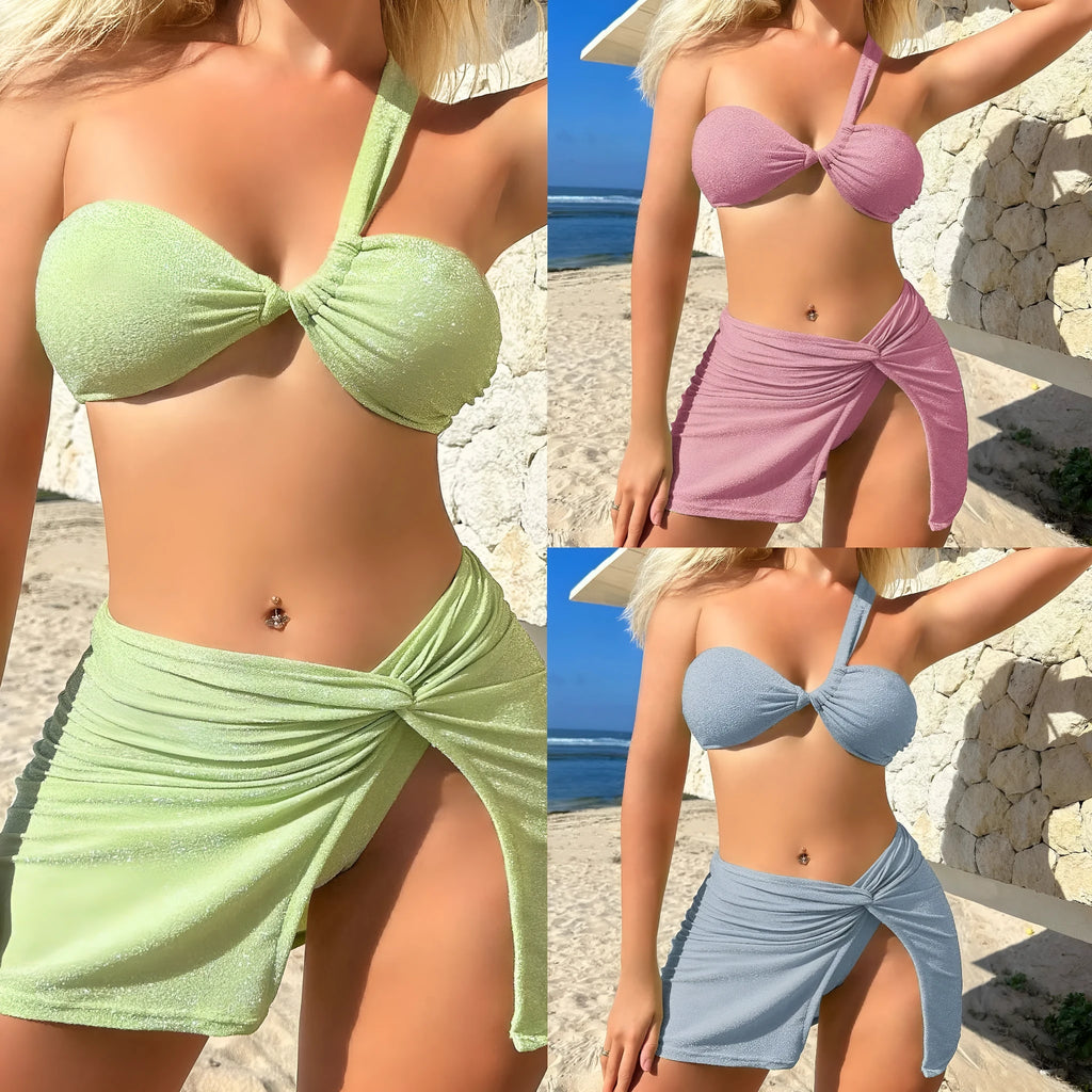 Light green one-shoulder swimsuit top, matching bikini bottoms, and cover-up skirt laid flat