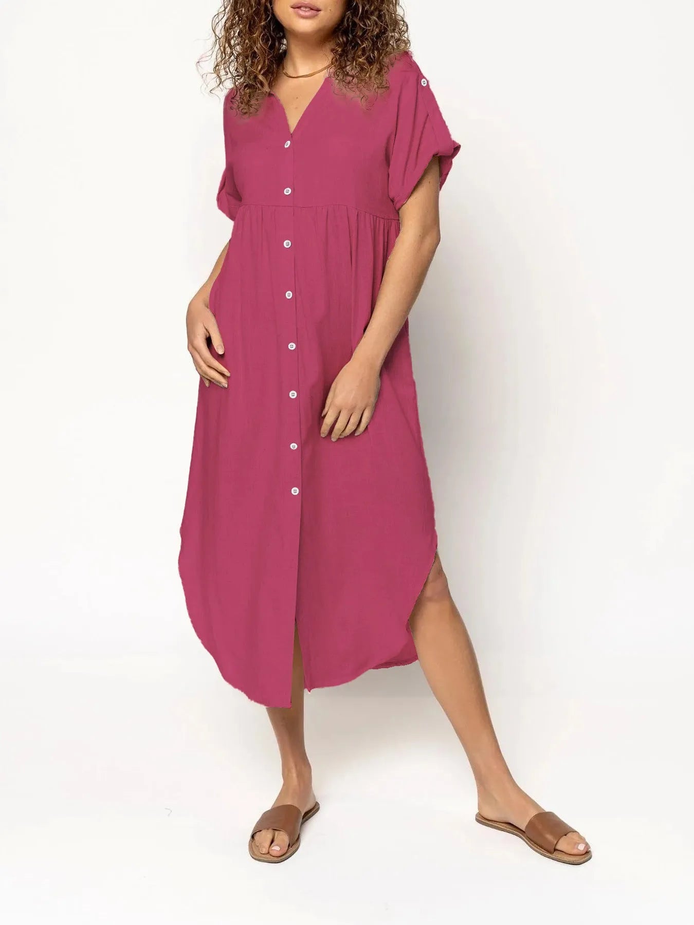 A woman wearing a loose-fitting, mid-length apricot-coloured casual dress with a button-down front.