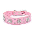 Close-up of a black PU leather dog collar with silver rhinestone flowers and studs, showing the metal D-ring.