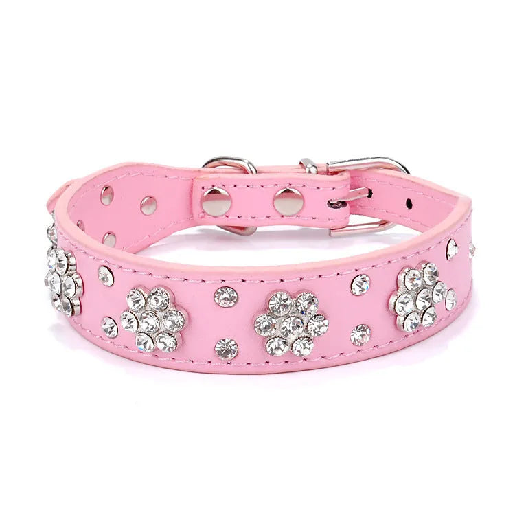 Close-up of a black PU leather dog collar with silver rhinestone flowers and studs, showing the metal D-ring.