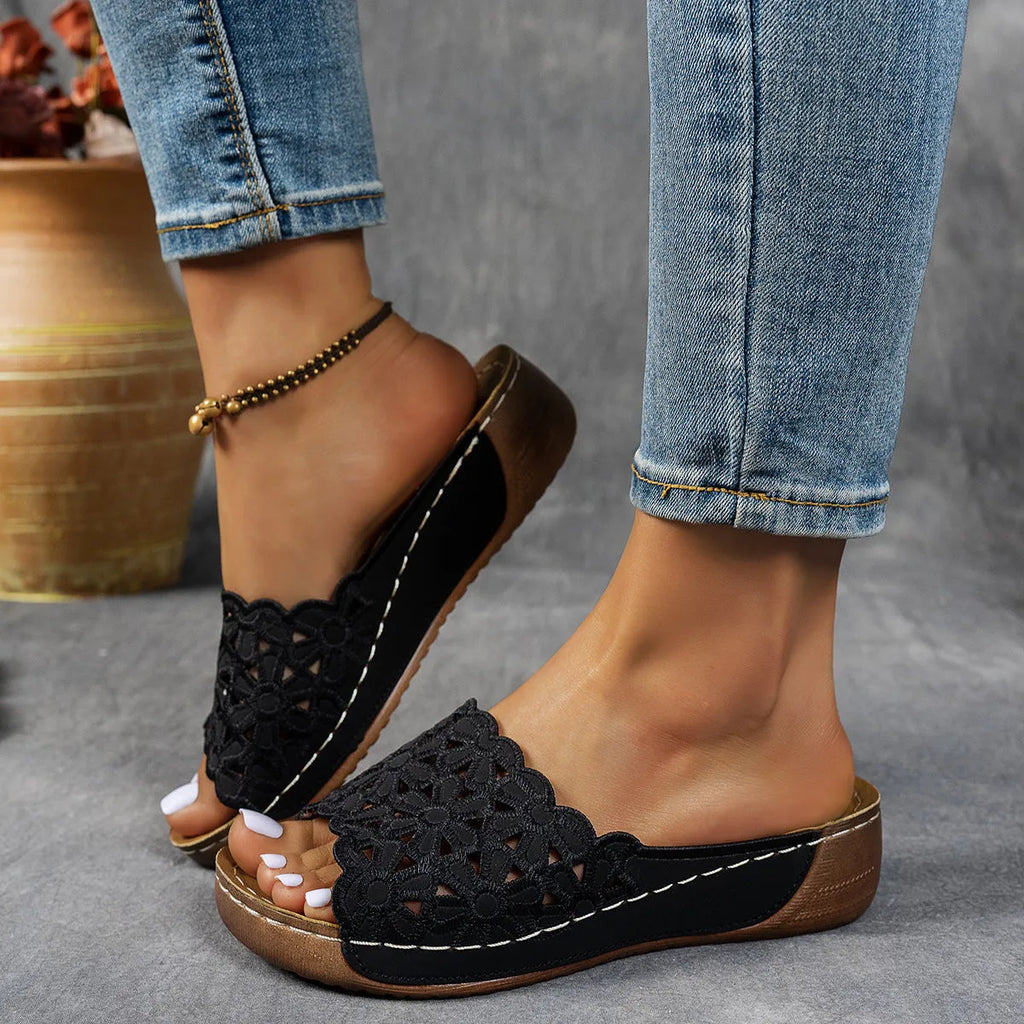 Black women's wedge beach sandals with a floral cutout pattern on the PVC upper.