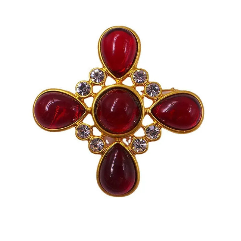 Close-up of a metallic medieval baroque cross brooch with crystal details on a dark background