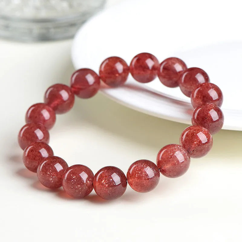 Natural cherry red strawberry quartz bracelet with polished geometric beads on a white background.