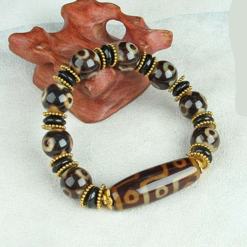 Distressed agate Tibetan bead bracelet with three-eye motifs and polished finish.
