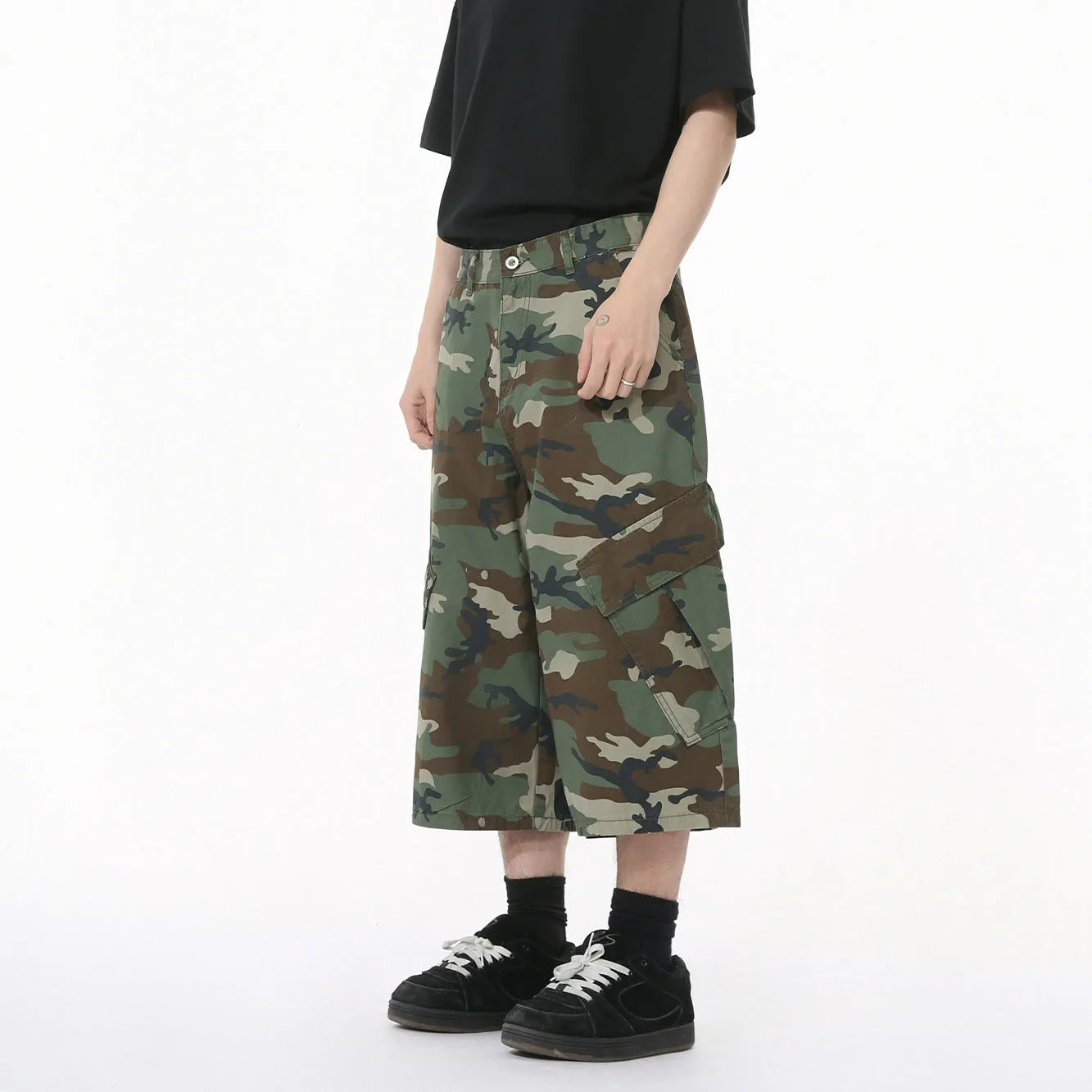 Men's loose-fit camouflage cotton trousers with wide legs, cropped hem, side stitching, and large front pockets.