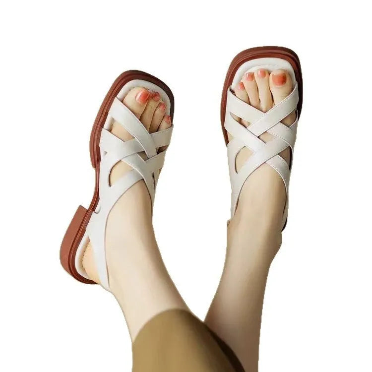 Women's glossy black patent leather sandals with a square toe and low heel on a rubber sole.