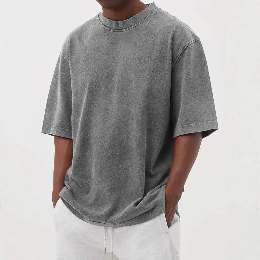 A man's loose-fit, stone-washed pullover t-shirt in a solid colour, shown on a hanger.