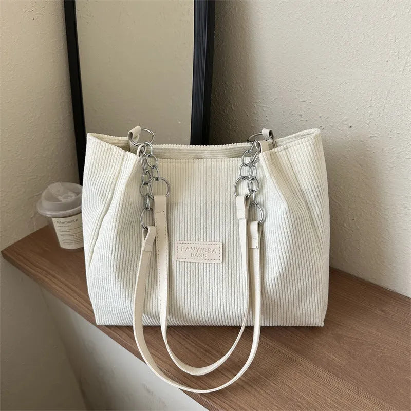 Corduroy one-shoulder tote handbag in a horizontal square shape with a three-dimensional outer pocket.