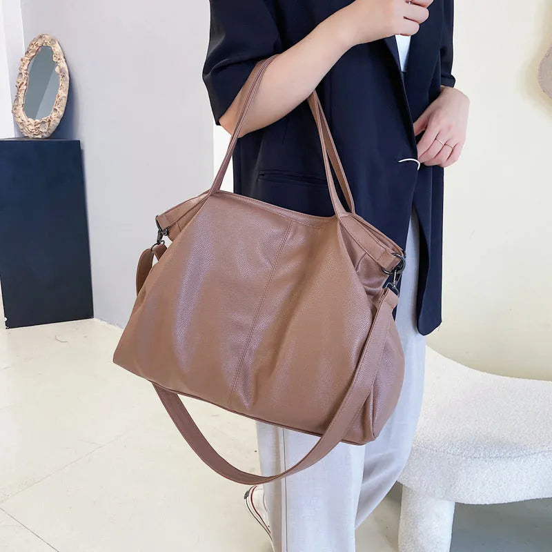 Large soft surface PU messenger bag in horizontal square shape with zip opening and shoulder strap.