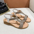 Gold women's patent leather sandals with rhinestone detailing and a non-slip sole on a sandy beach.