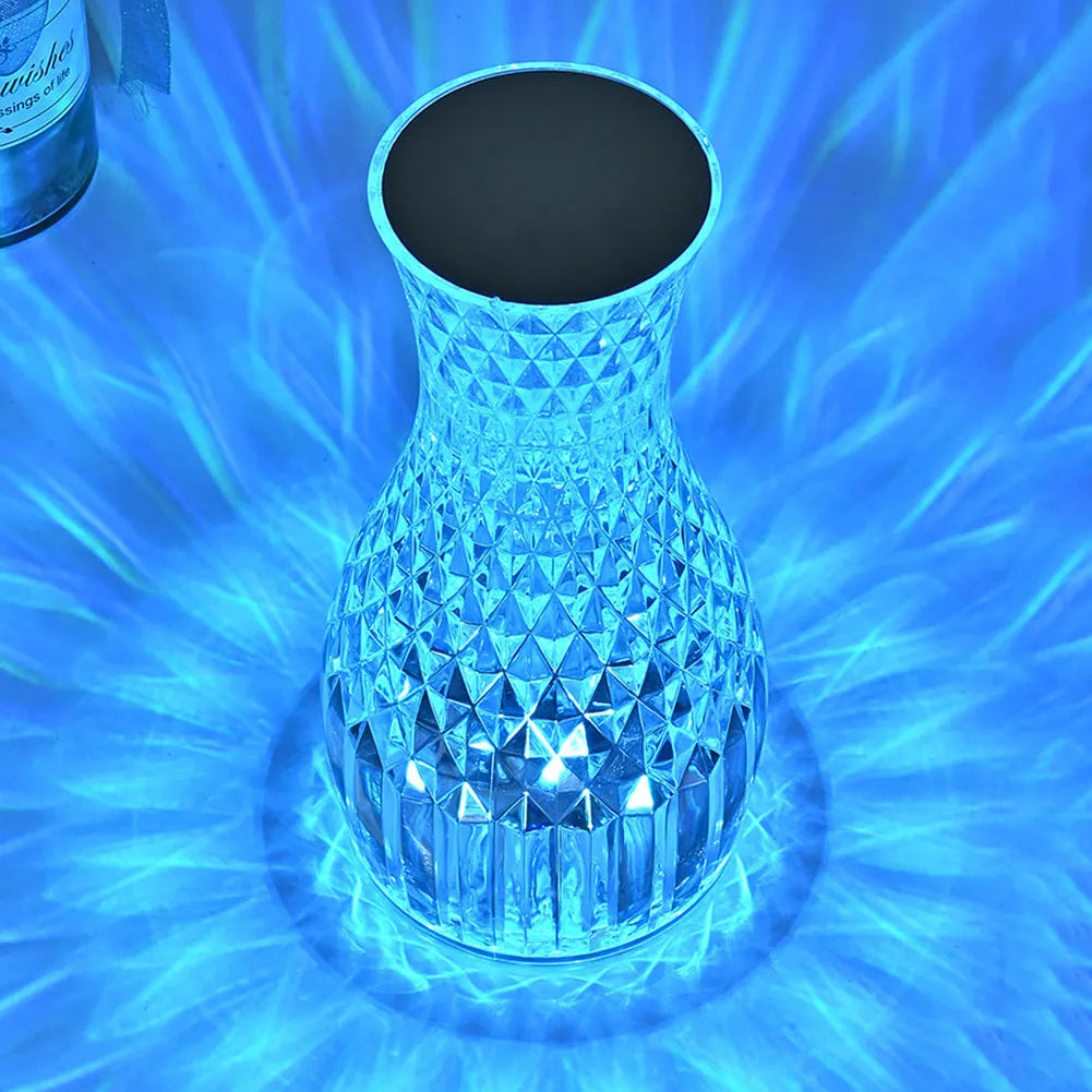 Vase-shaped transparent crystal table lamp with LED colour-changing lights on wooden surface