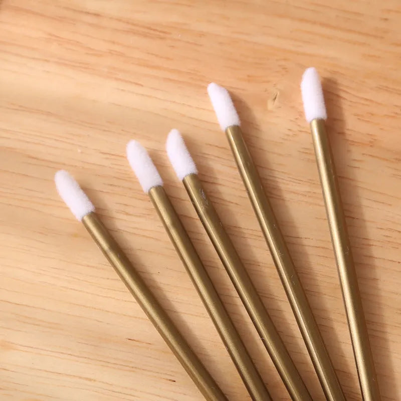 Pack of disposable flocked lip brush applicators with coloured handles on a white surface.
