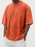 A man's loose-fit, stone-washed pullover t-shirt in a solid colour, shown on a hanger.