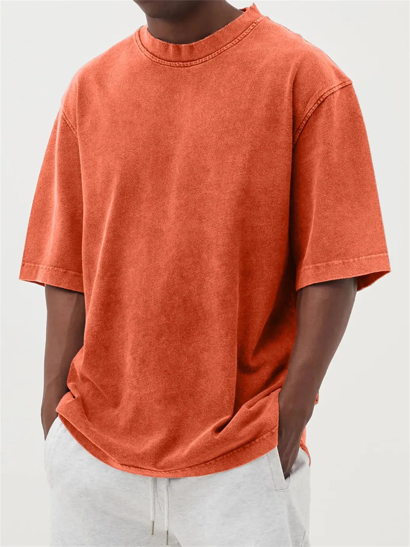 A man's loose-fit, stone-washed pullover t-shirt in a solid colour, shown on a hanger.