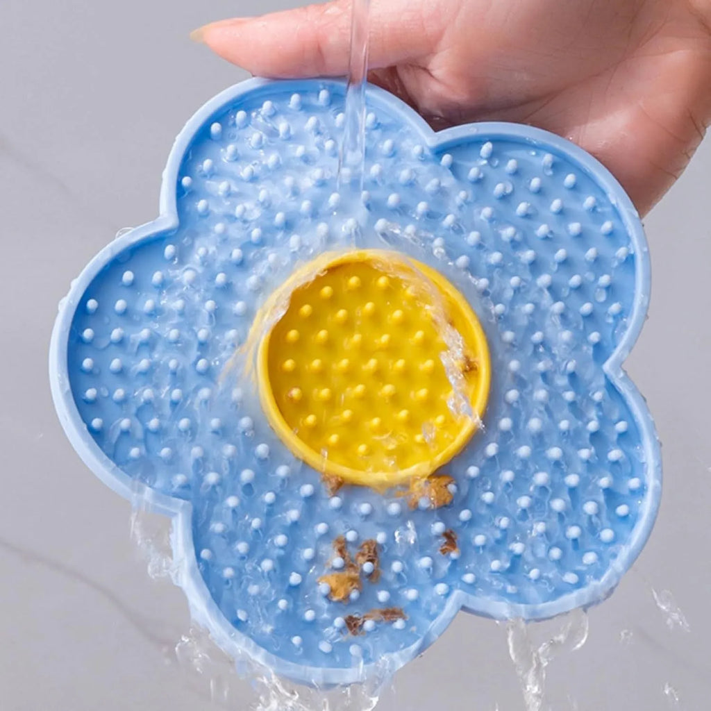 Flower-shaped blue silicone pet licking mat with suction cups on a smooth surface.