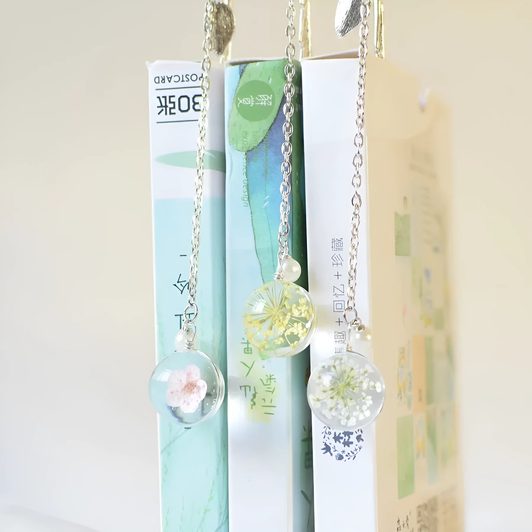 Alloy metal bookmark pendant with dried flower specimen, showing colour options on a 12 cm scale.