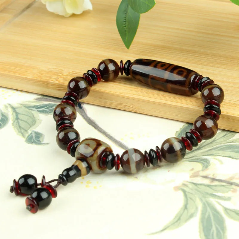 Distressed agate Tibetan bead bracelet with three-eye motifs and polished finish.