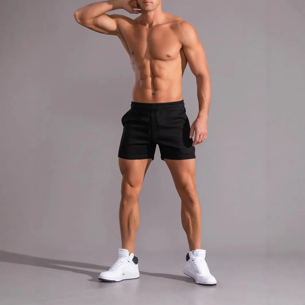 Three pairs of men's solid colour elastic shorts in black, khaki and light brown on a white background