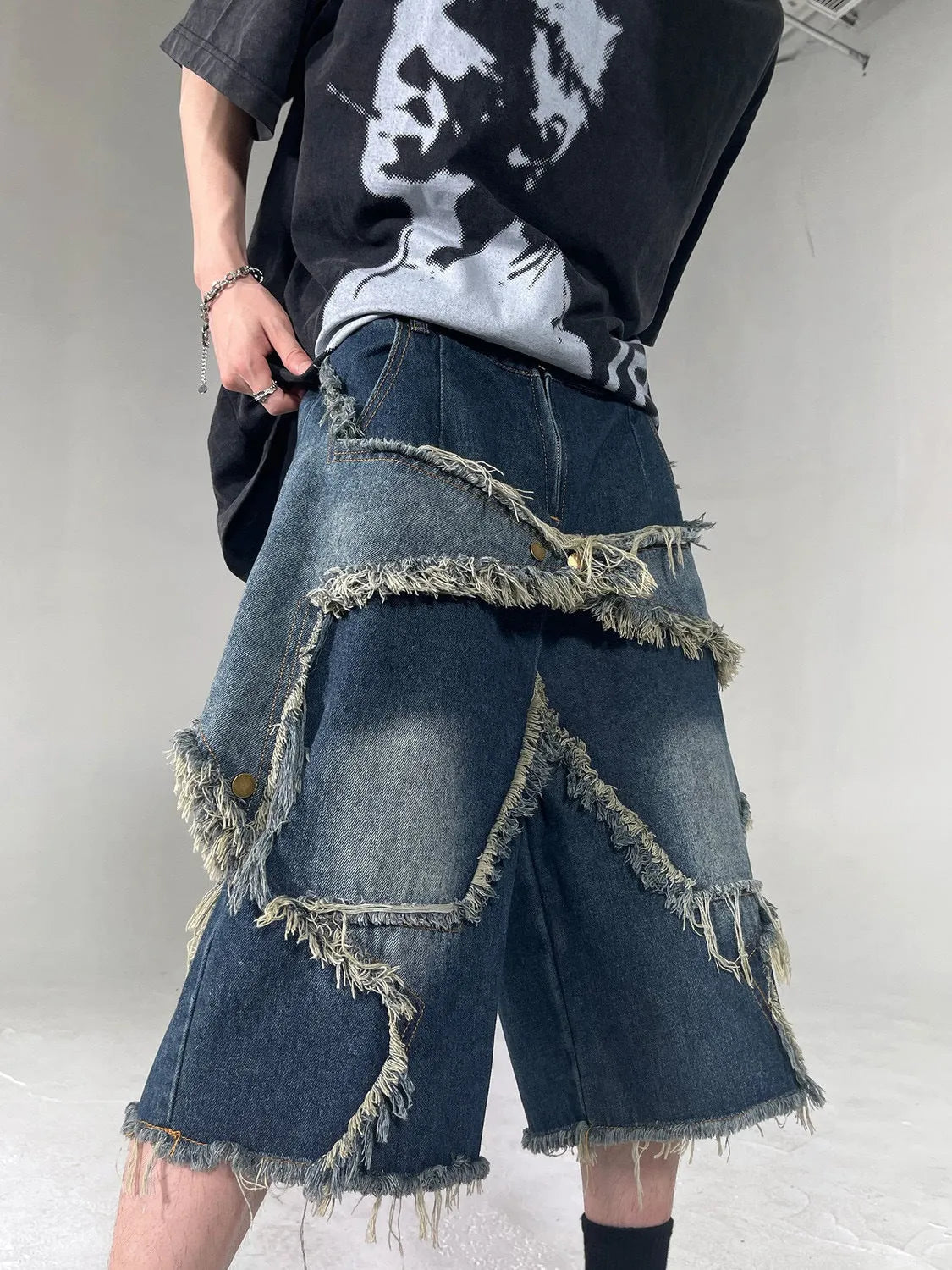 Blue loose-fit men's denim shorts with a frayed hem and a large retro star design on the leg.