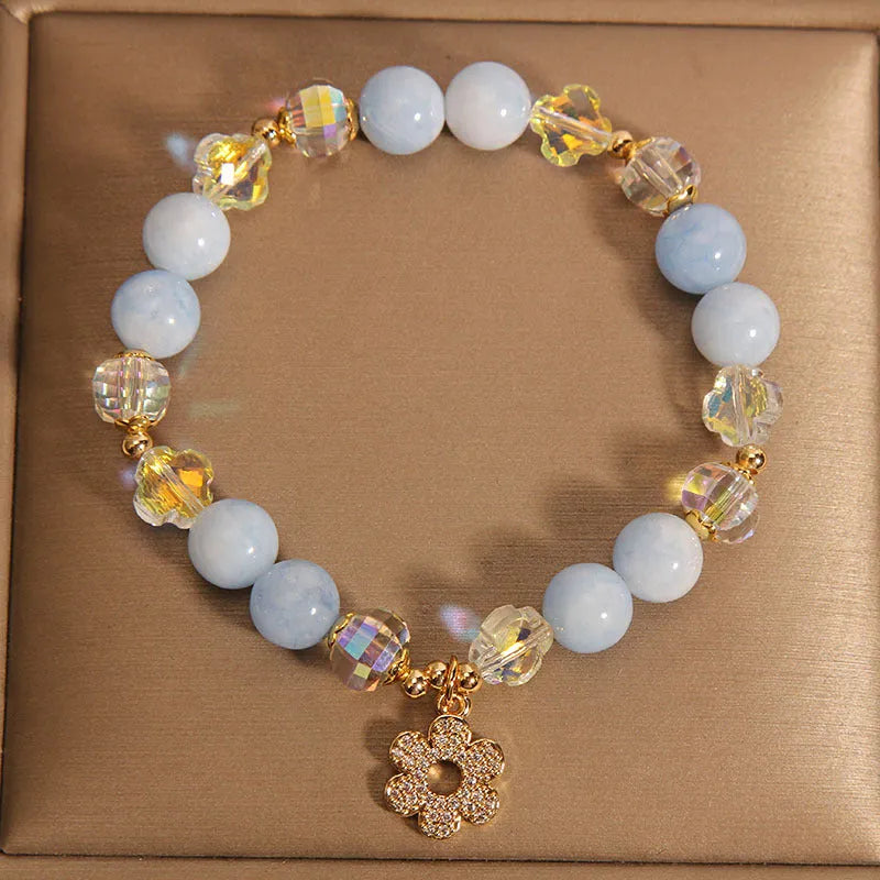 Women's aquamarine crystal bracelet with four-leaf clover charm and pearl accents on wrist