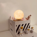 Maglev Moon Earth planet night light floating above base with LED glow, next to astronaut figurines.