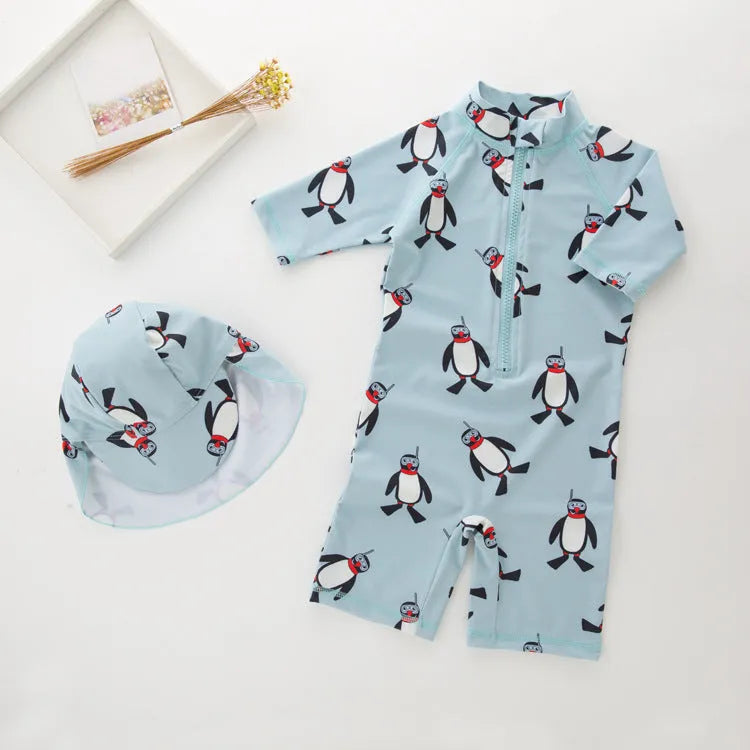 Boy's long sleeve penguin print swimsuit set with matching swimming cap on a white background.