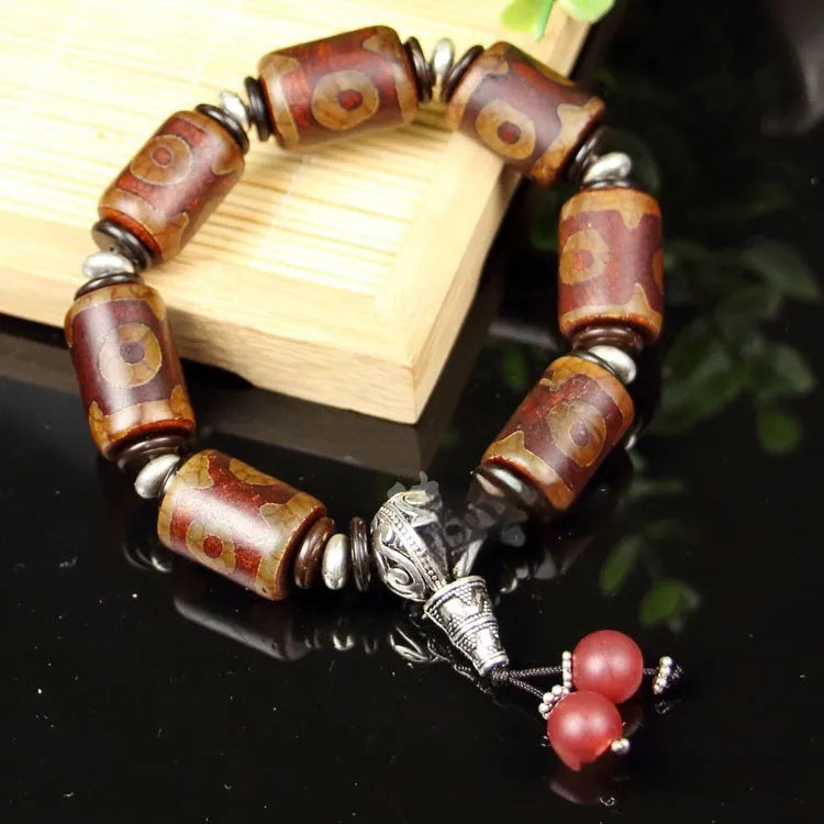 Distressed agate Tibetan bead bracelet with three-eye motifs and polished finish.