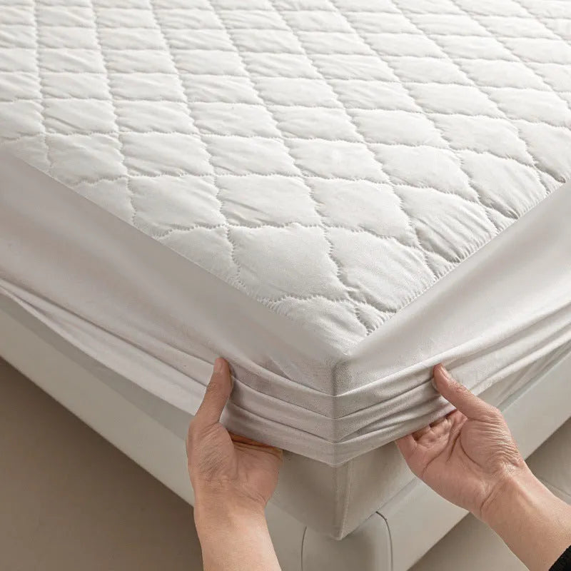 Diamond lattice quilted waterproof mattress protector fitted sheet in a solid colour on a bed.