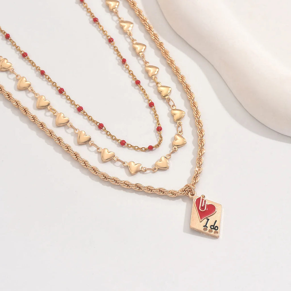Close-up of a three-layer zinc alloy clavicle chain necklace with geometric shapes and a heart pendant.