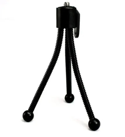 Small silver iron mini tripod with ball head, folded to compact size next to a smartphone.