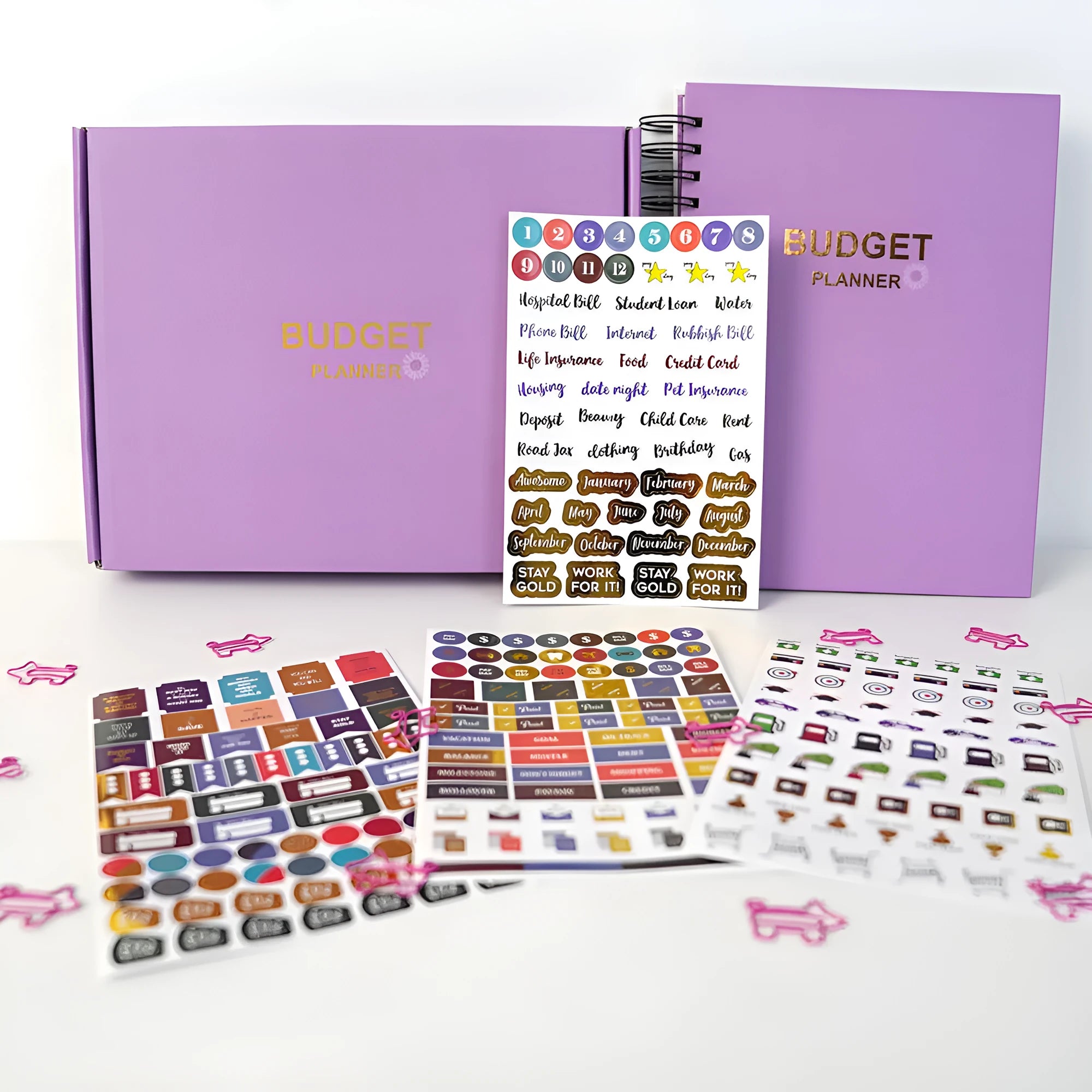 Purple coil-bound budget planning notebook with pen, stickers, and paper clips for financial organisation