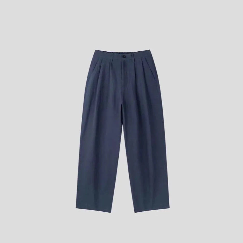 Man wearing loose fit apricot wide-leg cotton linen trousers with a zip fly and straight leg opening.