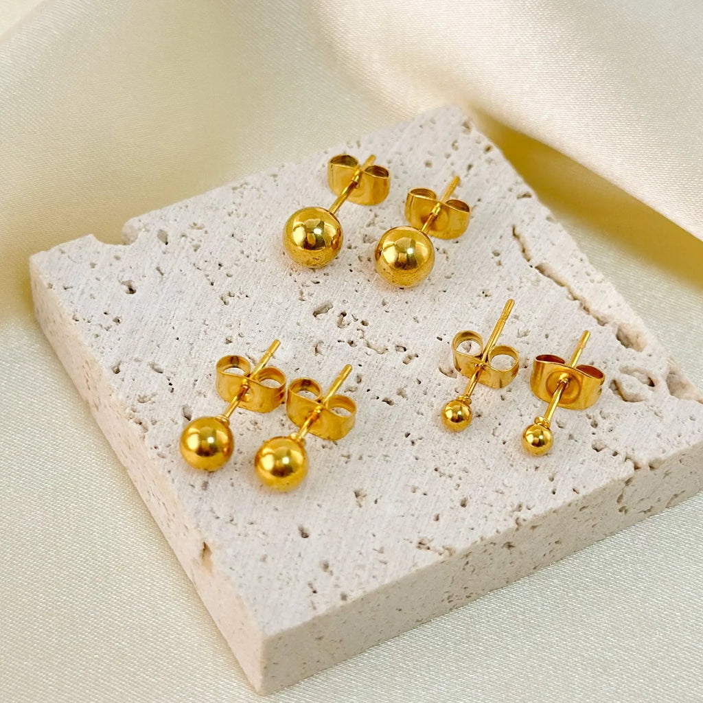 Stainless steel ball stud earrings with geometric design in gold or silver finish.