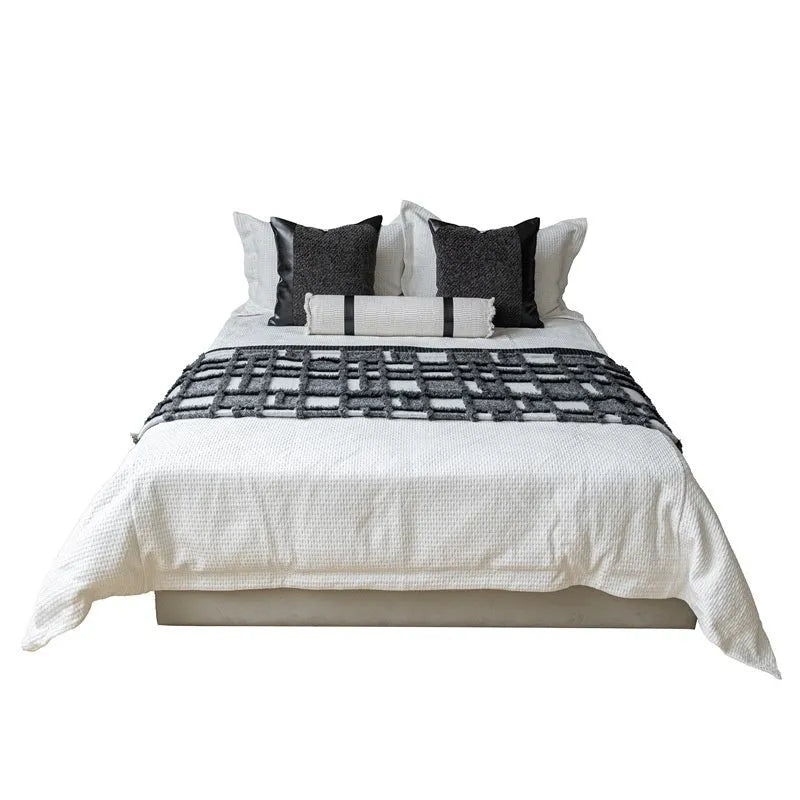 Modern minimalist grey and white plaid bed runner blanket with matching pillowcase and round leather pillow