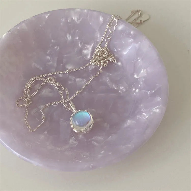 Women's sterling silver curb chain necklace with a geometric ornamental stone pendant on a grey background.