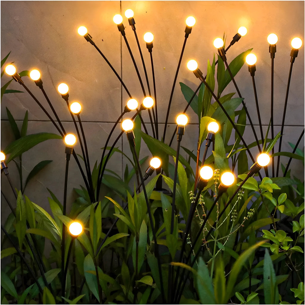 Solar-powered LED ground lamp with multiple heads inserted in garden soil alongside pathway